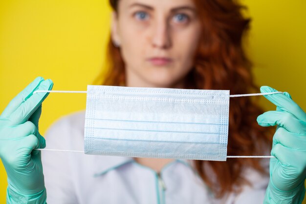 Het masker van de vrouwenholding om mond en neus te behandelen tegen virus op gele achtergrond te beschermen.