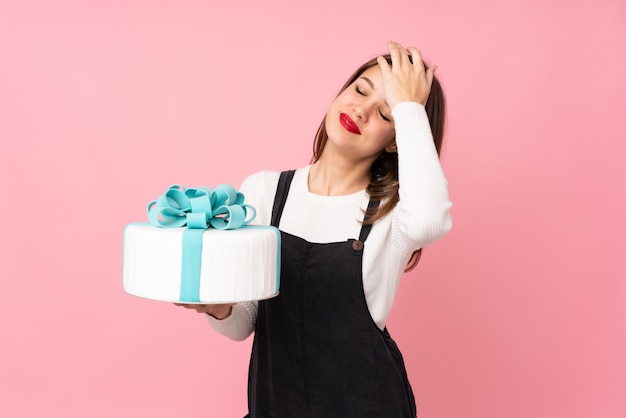 Het meisje dat een grote cake op roze houdt heeft iets gerealiseerd en van plan de oplossing