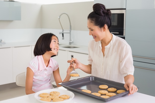 Het meisje dat haar moeder bekijkt bereidt koekjes in keuken voor