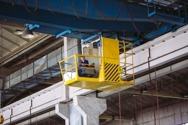 Het meisje dat in de cabine van een kraan werkt. Zware industrie, metaalfabriek.