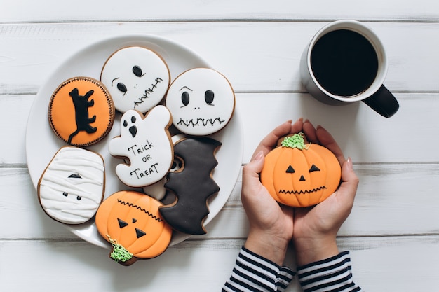 Het meisje dat zich voor Halloween voorbereidt, koffie drinken en lekkere peperkoekjes eet.