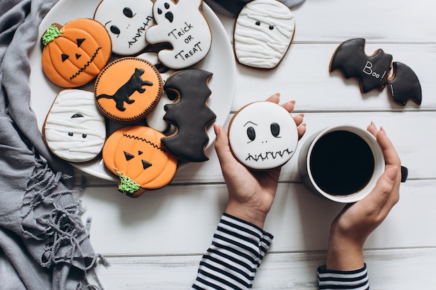 Het meisje dat zich voor Halloween voorbereidt, koffie drinken en lekkere peperkoekjes eet.