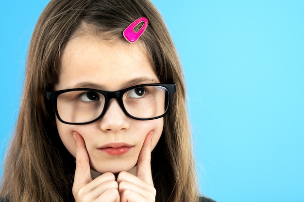 Het meisje die van de kindschool het kijken glazen dragen die hand houden aan haar gezicht het denken