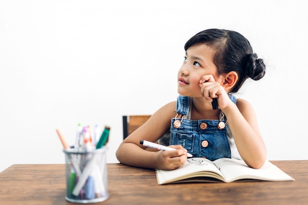 Het meisje die van het schooljonge geitje en in notitieboekje met potlood leren schrijven die thuiswerk maken