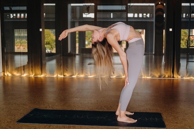 Het meisje doet yoga een vrouw in sportkleding doet yoga-oefeningen in de sportschool