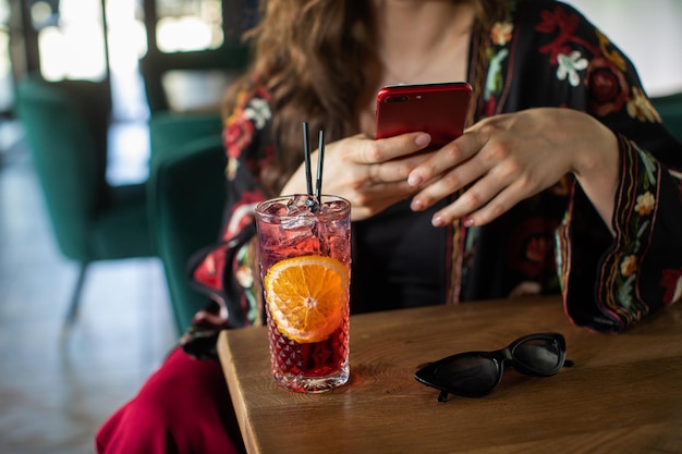 het meisje drinkt een heerlijke zoete cocktail en kijkt in de telefoon geweldige ontspannende dag