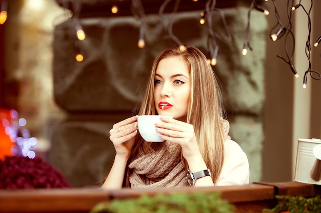 Het meisje drinkt een latte met schuim in een straatcafé
