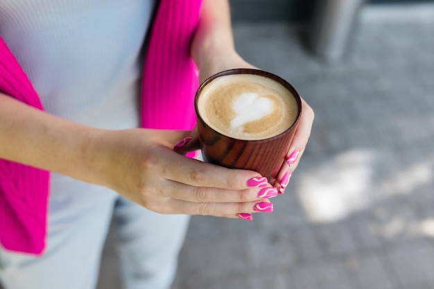 Het meisje drinkt koffie Meisje houdt koffie in haar handen Heerlijke cappuccino in de handen van een meisje Koffie en cappuccino in de hand Goedemorgen Heerlijke koffie