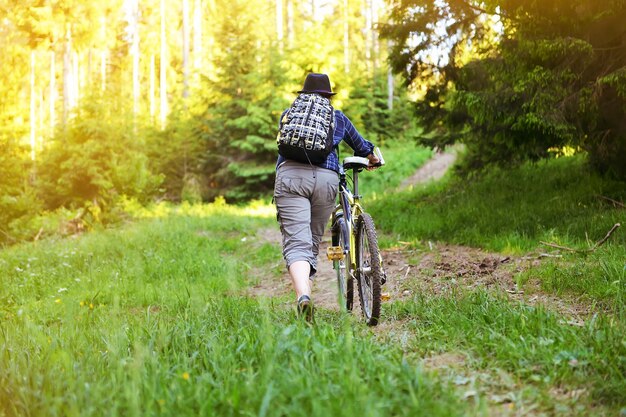 Het meisje fietst in het bos in de zomer in de bergen