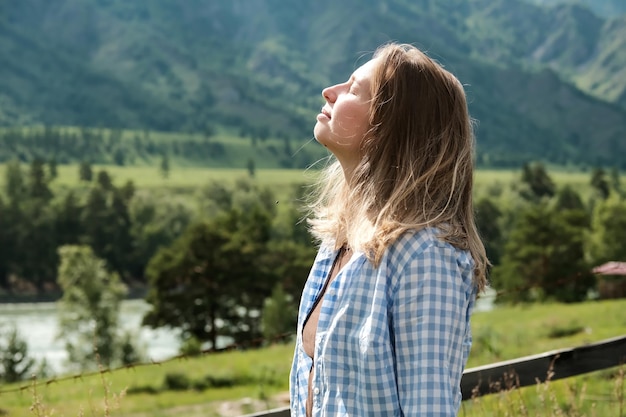 Het meisje geniet van de natuur Een blond meisje in de bergen geniet van de frisse lucht