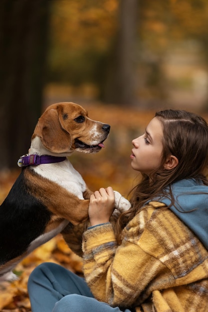 Het meisje houdt een Beagle-hond bij de poten. Herfst achtergrond.