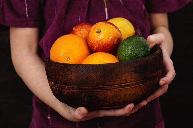 Het meisje houdt een kom citrusvruchten in haar handen