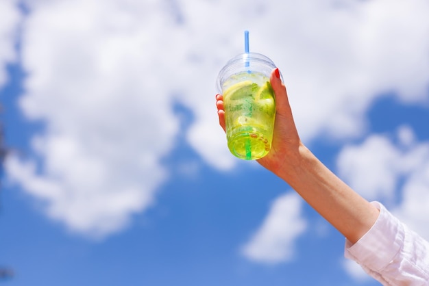 Het meisje houdt in haar hand een verfrissende zomercocktail in de stad