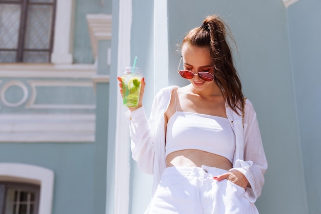 Het meisje houdt in haar hand een verfrissende zomercocktail in de stad