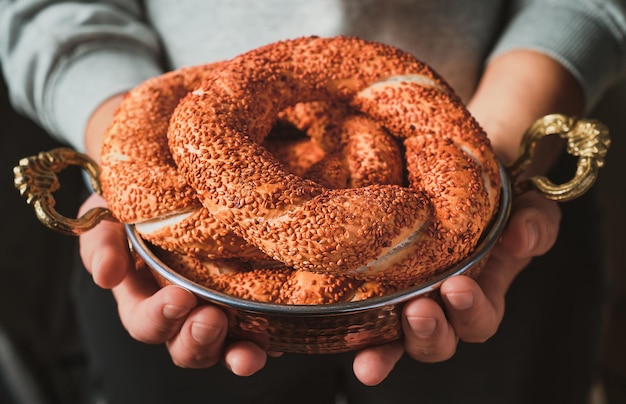 Het meisje houdt verse simit in haar handen in een koperen dienblad een versgebakken Turkse bagel close-up ontbijtidee