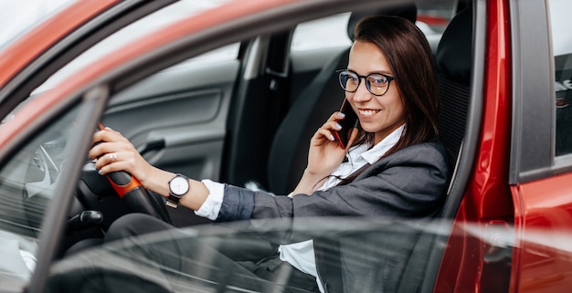 Het meisje in de auto achter het stuur kijkt naar de notificatietelefoon