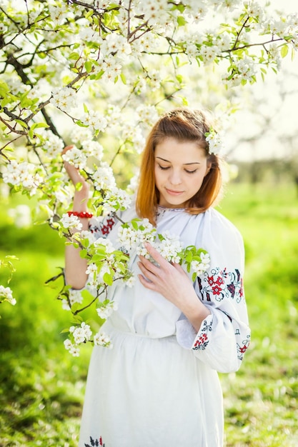 Het meisje in de bloemrijke tuin Lenteochtend in een prachtige tuin Oekraïens meisje