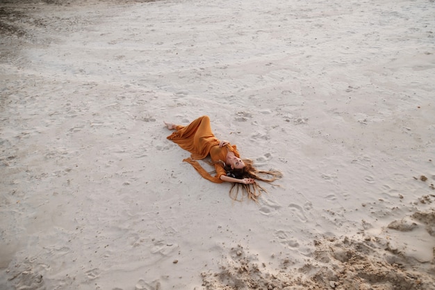 Het meisje in de cape ligt op het zand