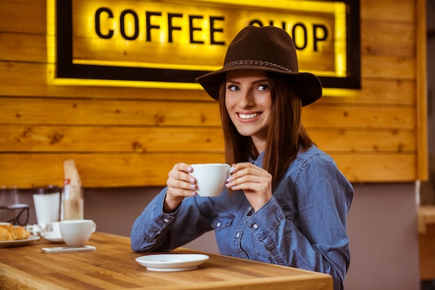 Het meisje in de dop drinkt koffie en glimlacht.