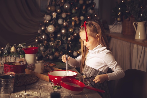 Het meisje in de keuken maakt koekjes klaar. Kerstversiering, familietradities, kerstvoedsel, vakantieavond.