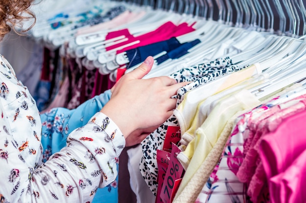 Het meisje in de modewinkel kiest een blouse voor de zomer