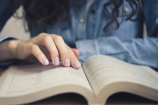 Het meisje in een denimoverhemd leest een boek