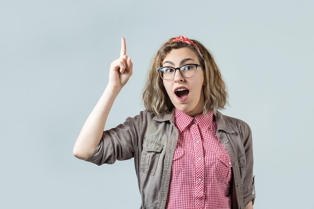 Het meisje in een rood geruit overhemd heft een gebalde vuist op van vreugde Succes en geluk van het werk Succesvolle persoonsoverwinning