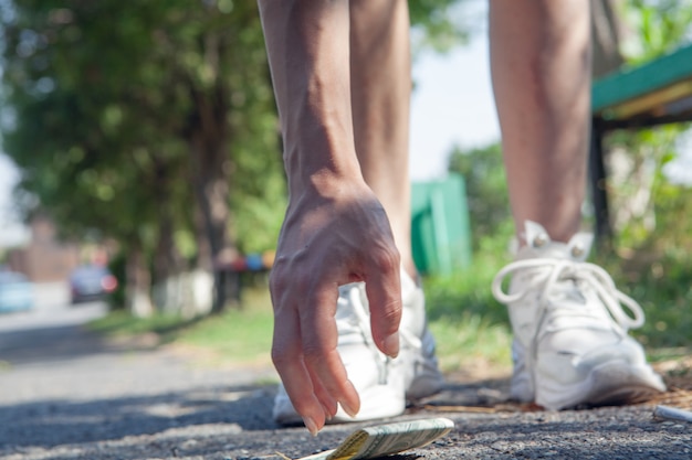 Het meisje in het park raapt geld op van de grond