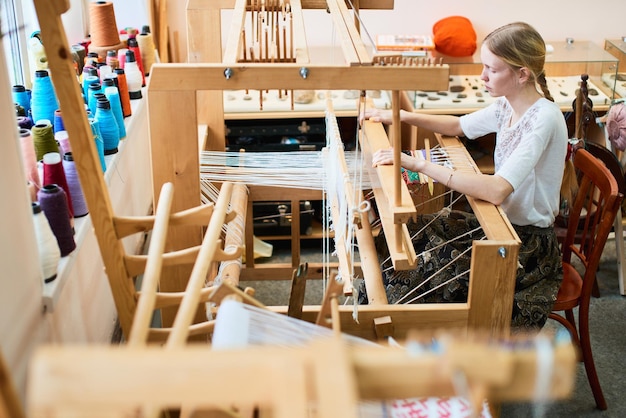 Het meisje in het productieproces van textiel is handgemaakt op een weefgetouw