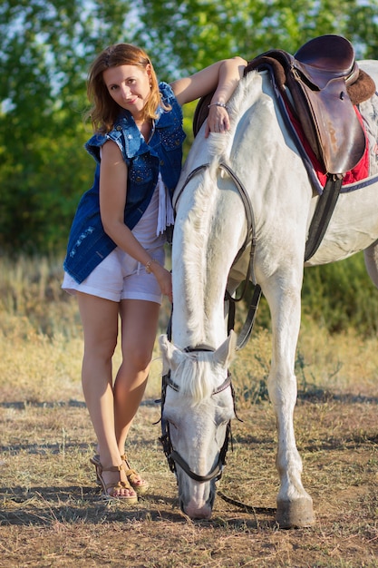 Het meisje in korte broek omhelst een wit paard