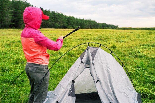 Het meisje in roze jasje met kap zet tent op