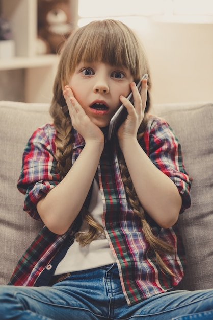 Het meisje in vrijetijdskleding spreekt op mobiele telefoon.