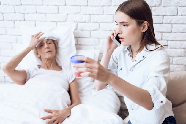 Het meisje is aan de telefoon en geeft pillen aan de vrouw.