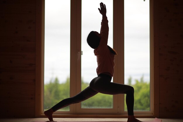 Het meisje is bezig met yoga op het tapijt voor het raam