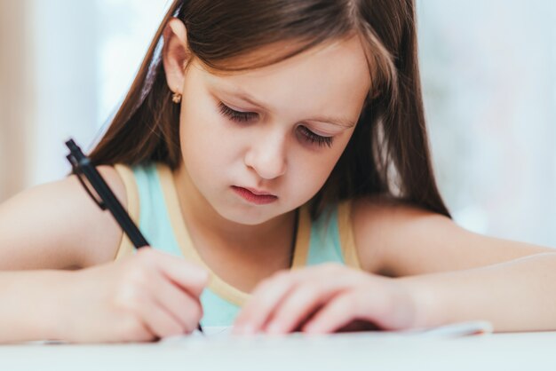 Het meisje is een eerste klas in de kamer die huiswerk maakt