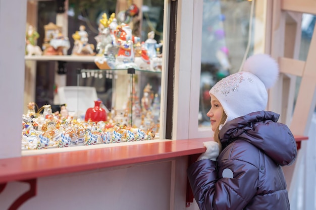 Het meisje kijkt naar het raam en kiest souvenirs Christmas Fair