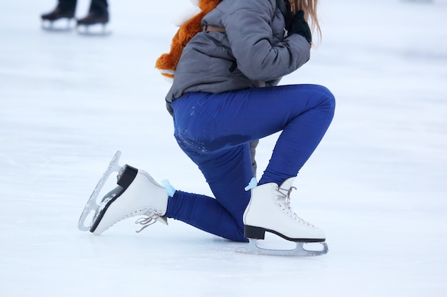 Het meisje klimt nadat ze op schaatsen is gevallen