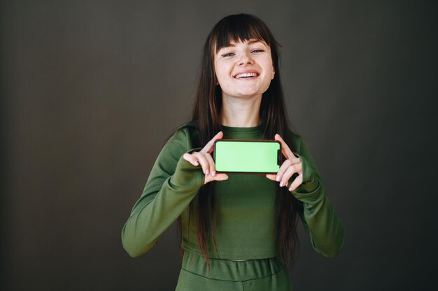 Het meisje lacht hardop en houdt de telefoon met beide handen vast met een groen scherm naar voren