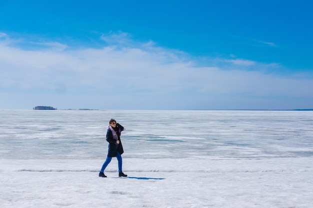 Het meisje loopt op de achtergrond van de ijzige zee en de blauwe lucht