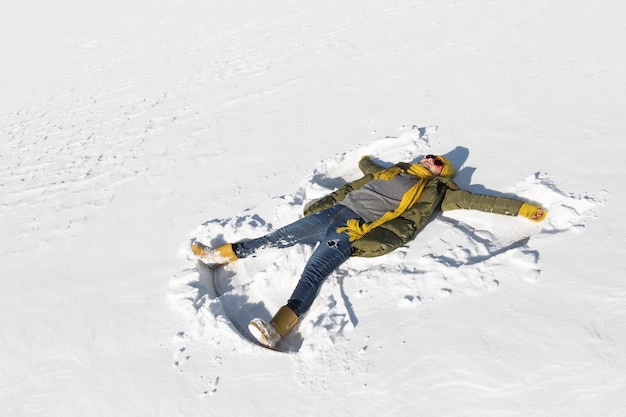 Het meisje maakt een engel in de sneeuw