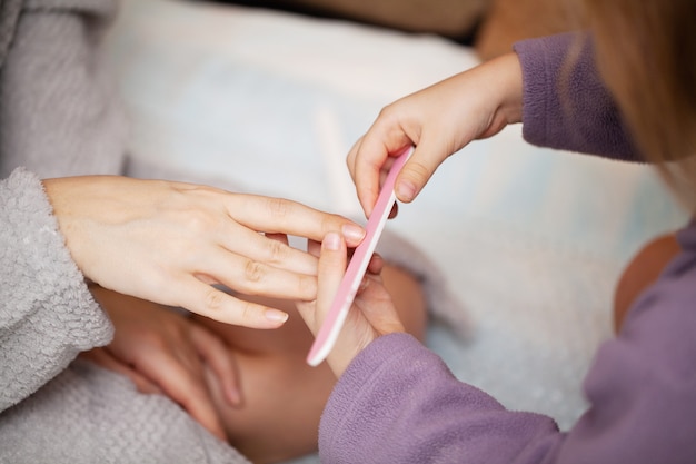 Het meisje maakt manicuremoeder, thuis in bed