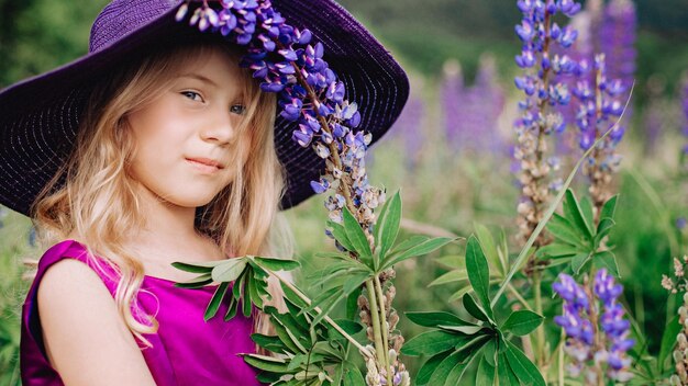 Het meisje met de hoed loopt in een veld met lupines.