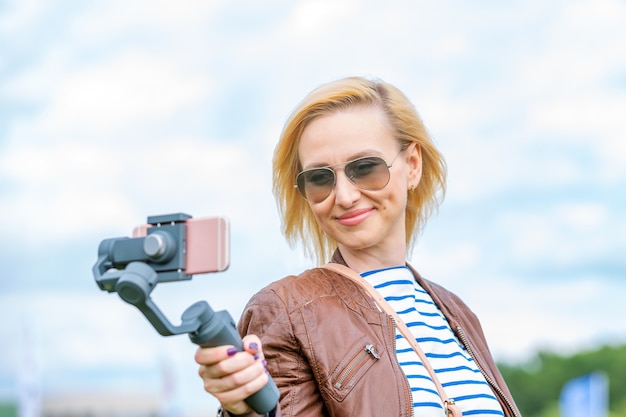 Het meisje met de telefoon op de stabilisator leidt de videoblog. Ze neemt zichzelf mee naar de camera Smartphone