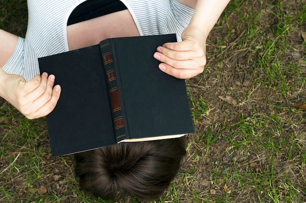 Het meisje met een boek ligt op het gras, hoogste mening