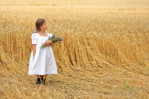 Het meisje met een boeket van wilde bloemen in haar dient een tarweveld in.