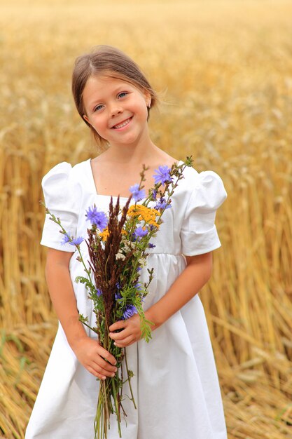 Het meisje met een boeket van wilde bloemen in haar dient een tarweveld in.