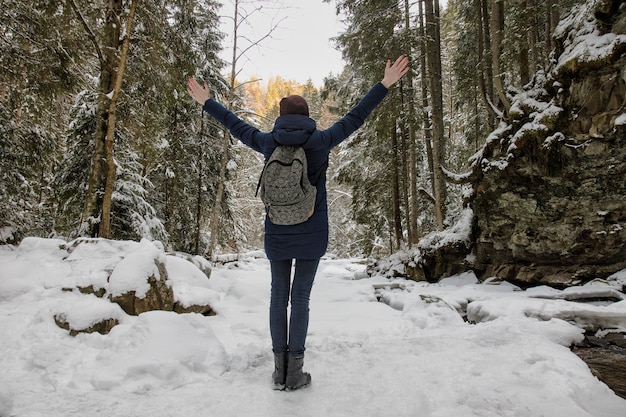 Het meisje met een rugzak bevindt zich met wapens die in een sneeuwbos worden opgeheven