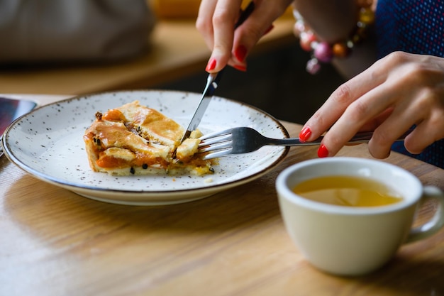 Het meisje ontbijt in een coffeeshop, eet een taart en drinkt thee