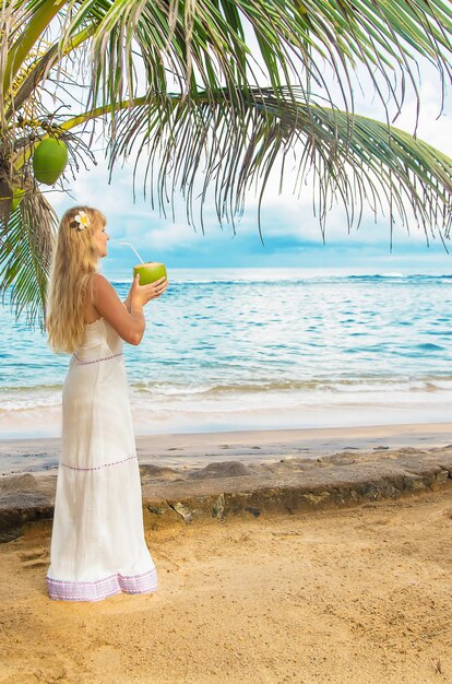 Het meisje op het strand drinkt kokosnoot