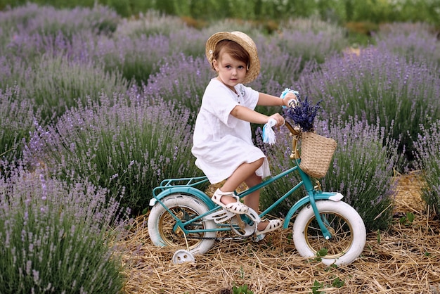 Het meisje rijdt op een fiets en rijdt op een lavendelveld.